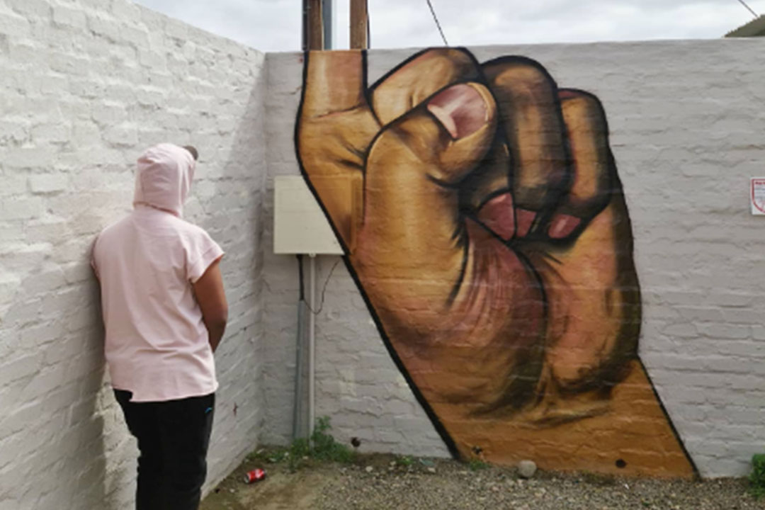 Graffitikunstwerk "I've got the power" : ein Mann steht vor einem Graffiti in Südafrika